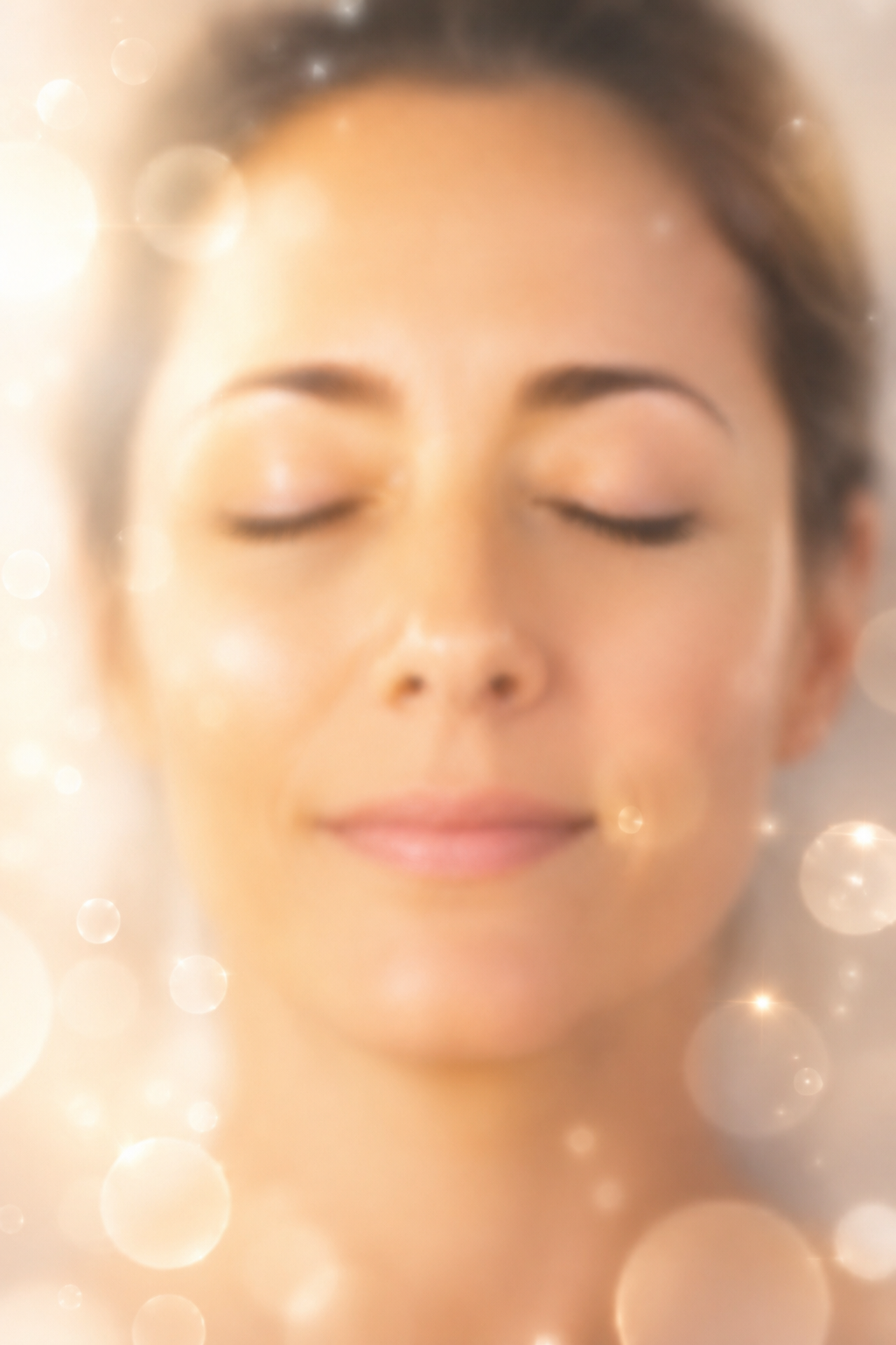 Close-up of a smiling woman with eyes closed, basking in a soft, warm glow.