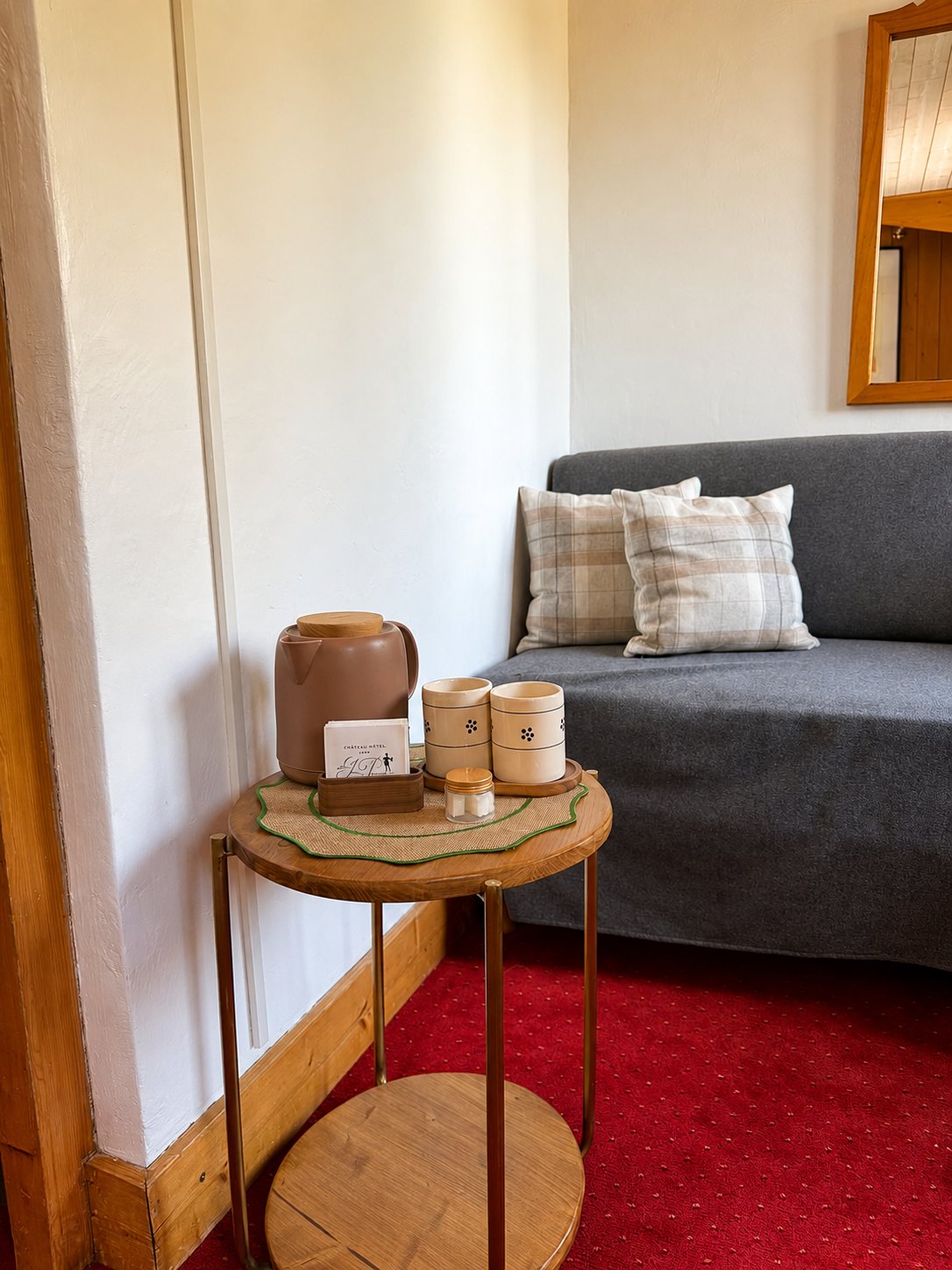 Coin salon avec canapé gris dans une chambre de l'Hôtel Jeu de Paume au Lavancher