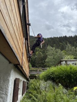 Yael en train d'escalader la façade en bois du restaurant Le Rosebud, Hôtel Jeu de Paume au Lavancher à Chamonix
