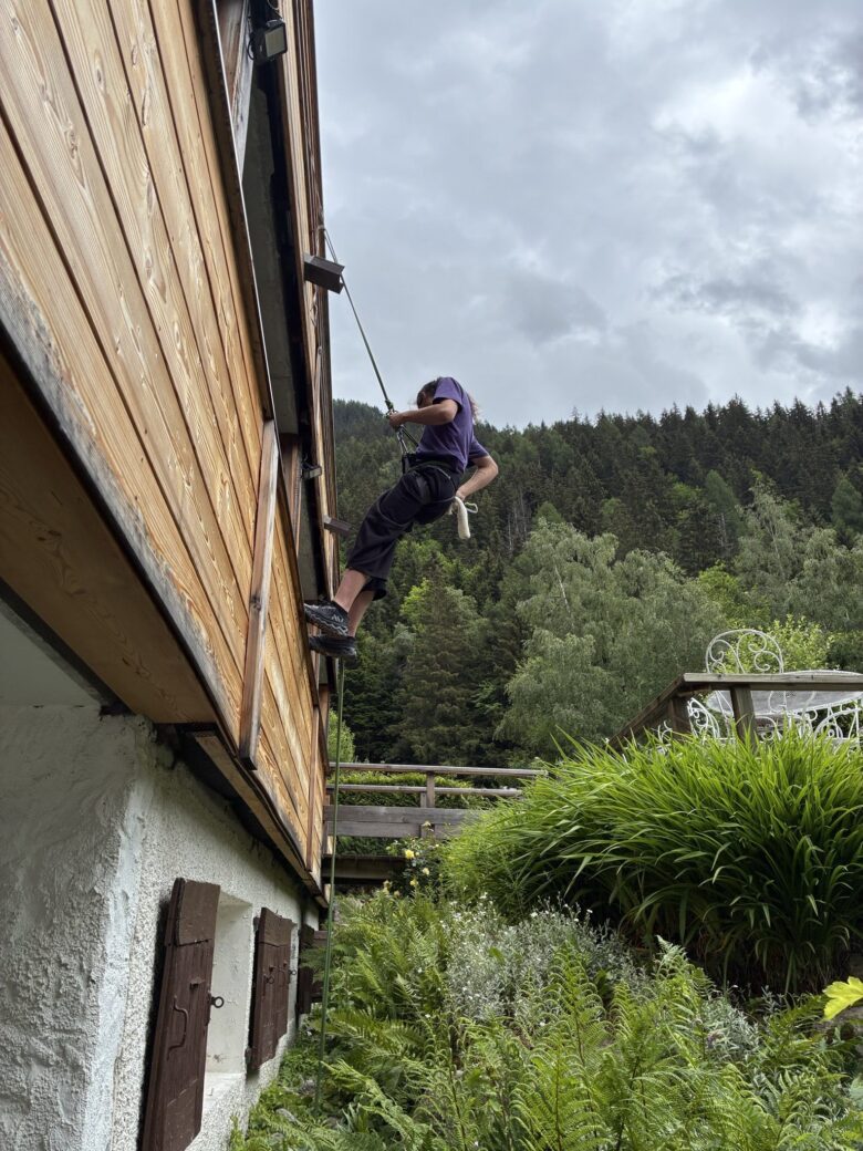 Yael en train d'escalader la façade en bois du restaurant Le Rosebud, Hôtel Jeu de Paume au Lavancher à Chamonix