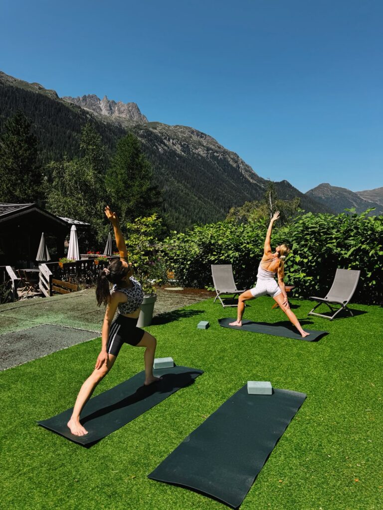Cours de yoga Vinyasa et Yin à Chamonix, posture du guerrier dans le jardin de l’Hôtel Jeu de Paume au Lavancher